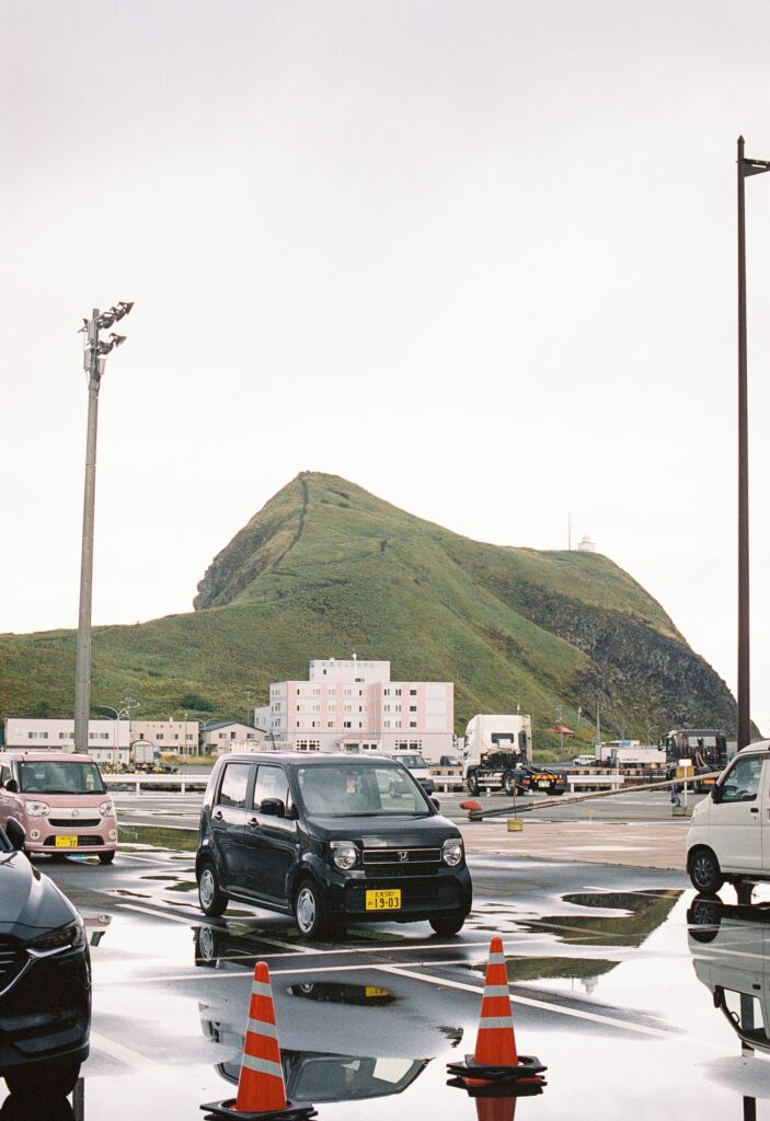 雨上がりの駐車場と、奥に見える緑の山