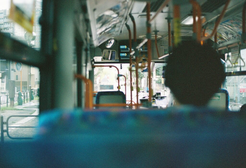 バスの車内で、前の席に座る人を後ろから写した写真