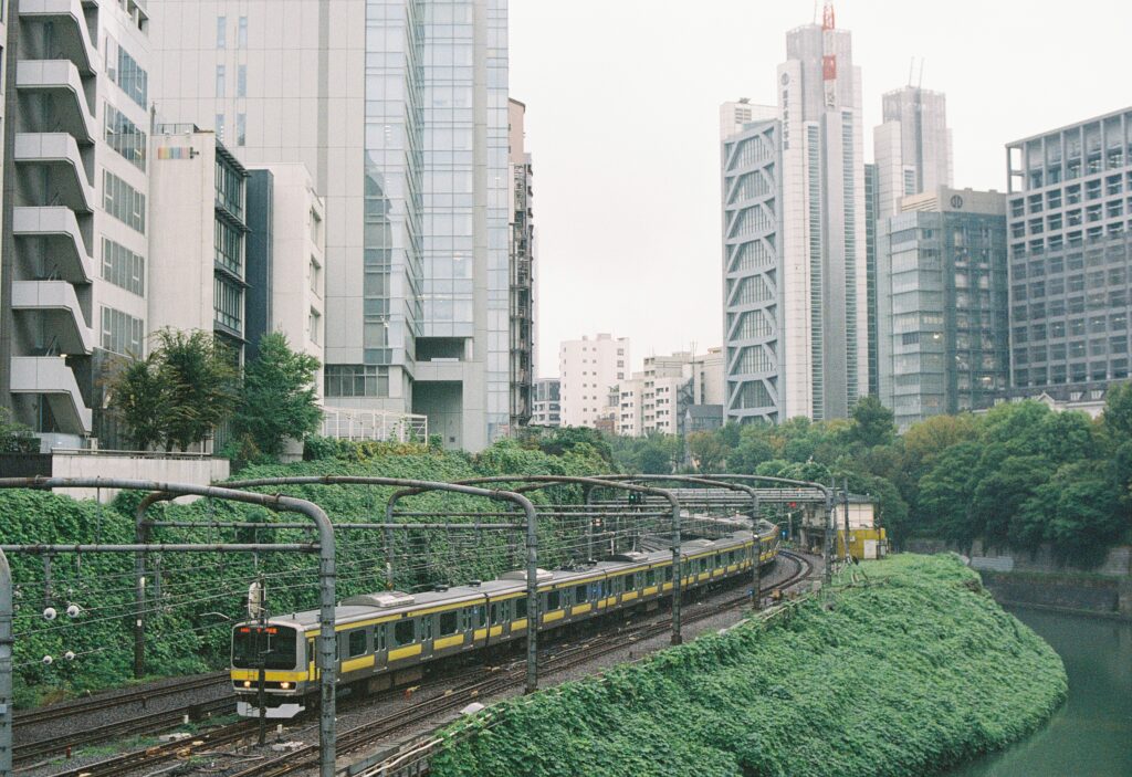 線路を走る電車と、奥に並ぶ高層ビル