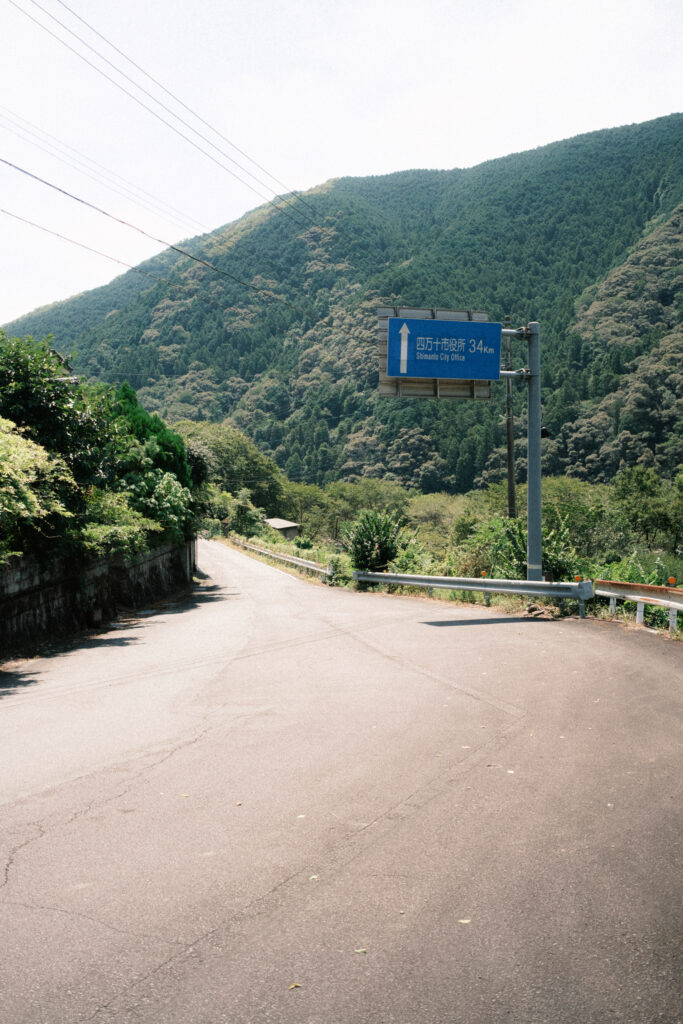 山あいの道と青い案内標識